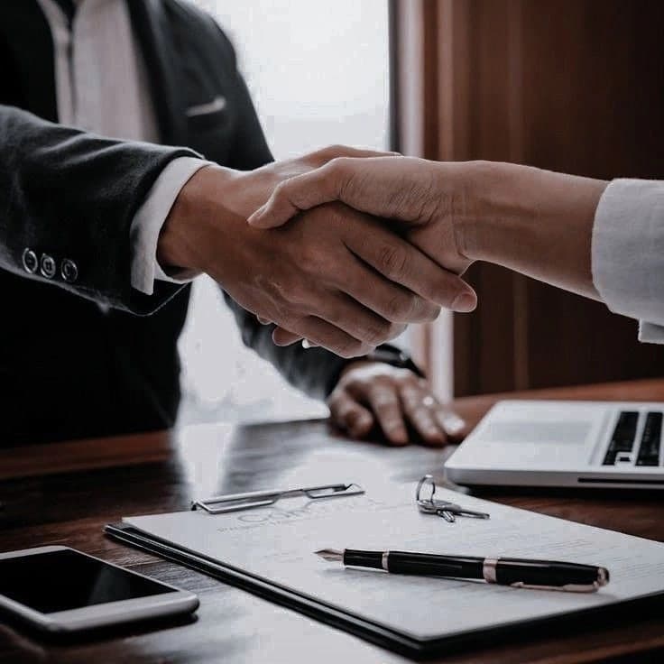 Business partners shaking hands across a desk